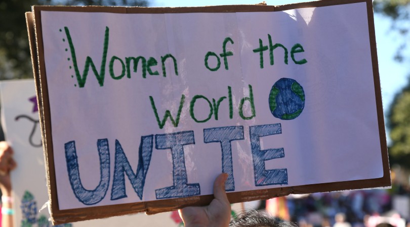 Pancarta: “Women of the World UNITE” (“Mujeres del mundo: UNÍOS”)