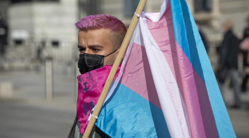 Una persona porta una bandera trans frente al Congreso, tras la convocatoria para denunciar el retraso en la tramitación de la ley trans. | David F. Sabadell